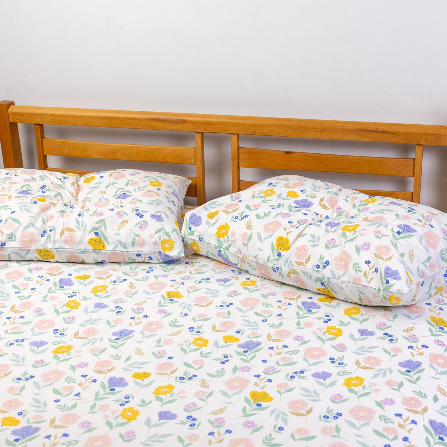 Floral patterned bedspread on a bed with wooden headboard and nightstand.