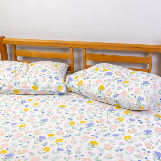 Floral patterned bedspread on a bed with wooden headboard and nightstand.